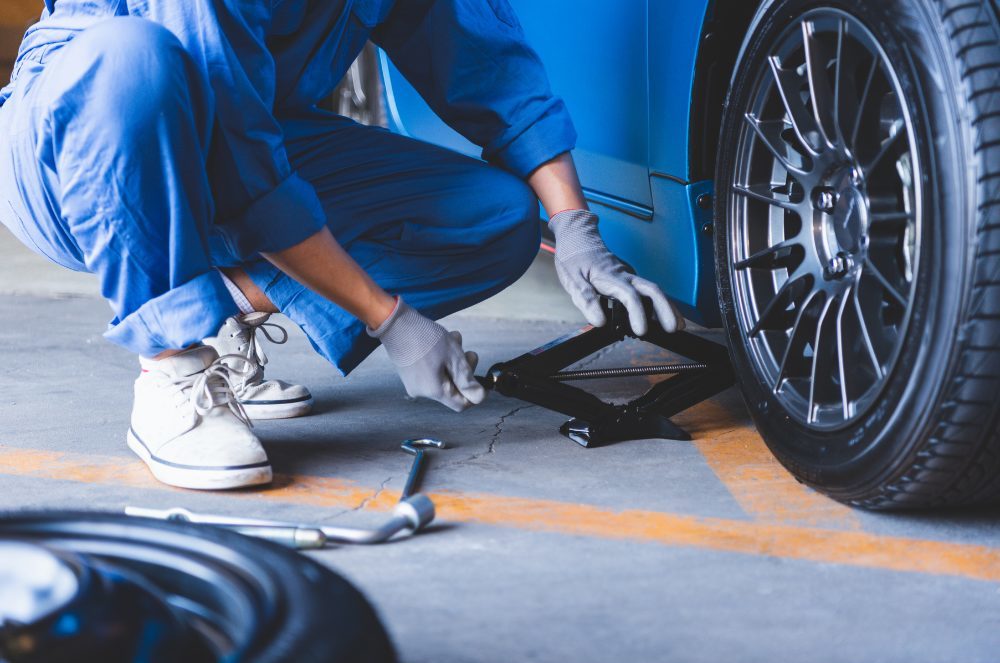 Mechanic in a car repair shop jacking up a car